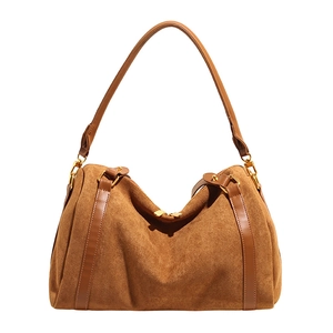 Détail du sac hobo en daim marron avec lanières en cuir lisse et boucles dorées