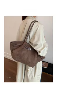 Detail view of brown matte bucket bag with adjustable silver buckles and thin straps