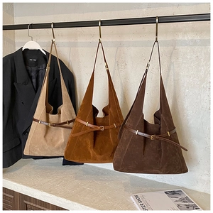Three suede tote bags in beige, caramel, and dark brown with delicate buckle details