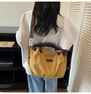 Detail view of ginger yellow canvas tote bag with brown straps in a lifestyle setting
