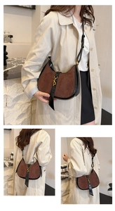Close-up of crescent bag showing brown suede and black leather with golden hook buckle