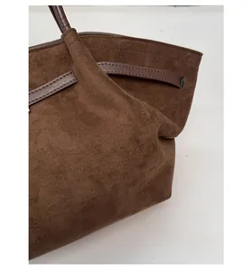 Detail of dark brown suede tote bag with reinforced leather handles and precision stitching