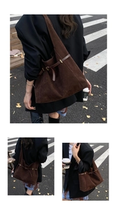 Detail of dark brown suede tote bag with leather strap and golden hardware accents