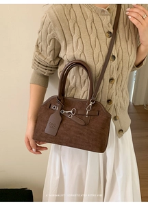 Close-up of vintage brown suede shell bag with silver ring and leather brand tag detail