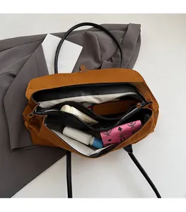 Top view of large suede tote bag interior showing multiple spacious compartments and black straps