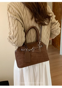 Detail of a brown leather tote bag showing retro straps and metallic eyelets on the side