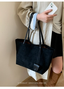 Dettaglio borsa tote nera in pelle scamosciata opaca con tracolla e ciondolo decorativo