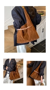 Detailed macro view of brown suede tote bag featuring a leather strap with golden buckle