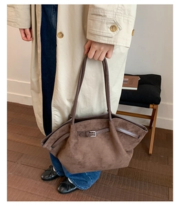 Close-up of matte dark brown tote bag featuring fine leather grain and buckle strap detail