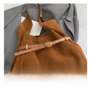 Close-up of brown suede tote bag featuring fine gold metal buckles and leather strap detail