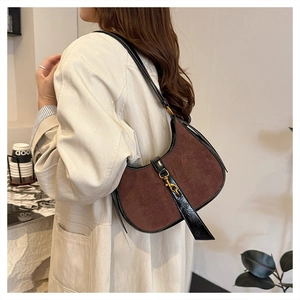Detail of a brown suede crescent bag with black leather trim and vintage gold metal buckle