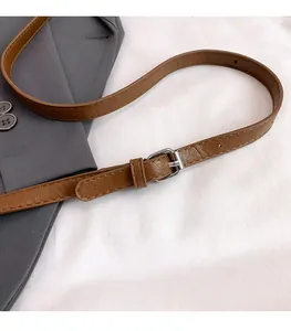 Dettaglio della tracolla regolabile in pelle marrone con fibbia argentata su borsa di peluche