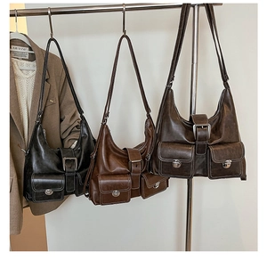 Detail of vintage faux leather tote bags in black and brown with utility pockets and metal buckles