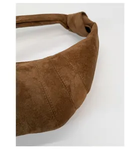 Détail d'un sac croissant en daim marron avec surpiqûres fines et bandoulière nouée