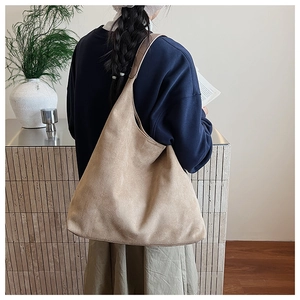 Detail shot of large khaki faux suede hobo bag carried on shoulder for casual commuting
