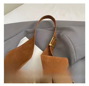 Detail showing brown suede tote bag with golden metal buckle and shoulder strap connector