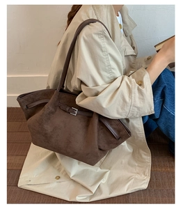 Detail of dark brown suede tote bag featuring a leather strap and metallic buckle closure