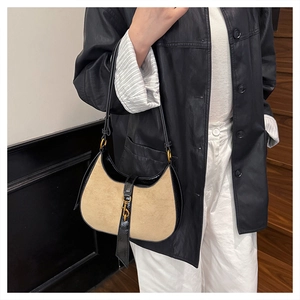 Detail of khaki suede crescent bag with black leather trim and golden piston closure