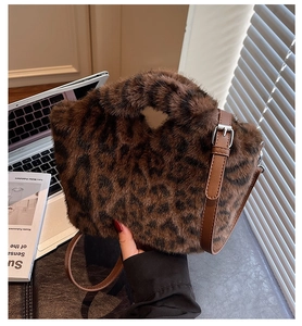 Leopard-Plüschbeuteltasche mit herzförmigem Griff auf Laptop und Buch Hintergrund