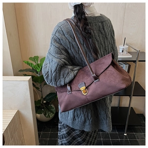 Detail of a large burgundy suede shoulder bag featuring a gold buckle on the strap