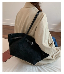 Close-up of the large black suede tote bag with stylish silver buckle on long trench coat