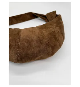 Vue détaillée du sac croissant en daim marron foncé avec coutures et poignée nouée