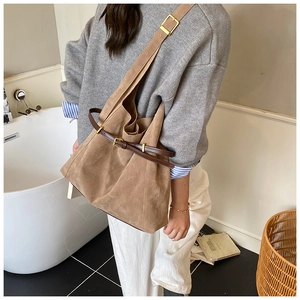 Détail du sac cabas en daim camel avec boucle en cuir marron et large bandoulière
