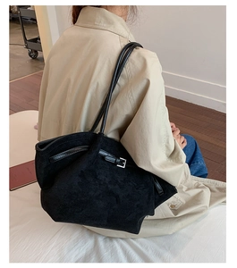 Side view of a black matte tote bag with shoulder strap and metal buckle detail