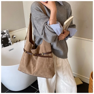 Close-up of large brown suede tote bag with leather strap and metal buckle detail