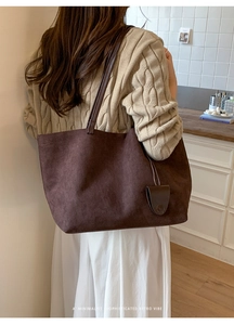 Dettaglio borsa tote in pelle scamosciata marrone con astuccio in ambiente caldo