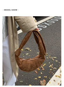 Détail du sac croissant en daim marron avec poignée nouée et structure plissée chic