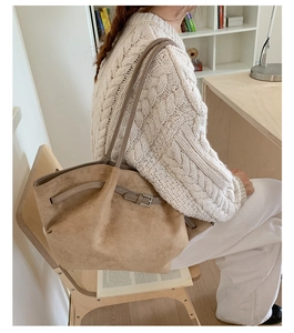 Detail of light brown suede tote bag featuring slim shoulder straps and decorative buckle