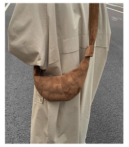 Détail d'un sac croissant en daim marron foncé avec coutures incurvées et sangle nouée