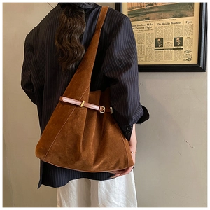 Détail d'un grand sac hobo en daim marron avec lanières en cuir et boucle dorée