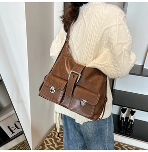 Detail of brown vintage crossbody bag featuring dual front pockets and silver buckles