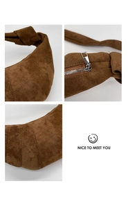Détail du sac croissant en daim marron foncé montrant la texture plissée et la sangle nouée