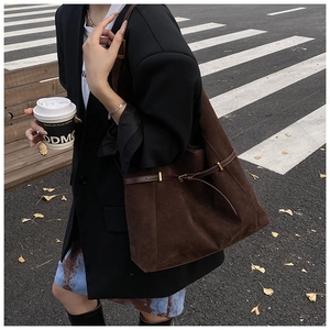 Détail latéral du sac cabas en daim marron avec fine sangle et boucle métallique dorée