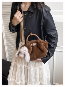 Dettaglio della borsa in peluche marrone con tracolla in pelle e ciondolo a coniglio