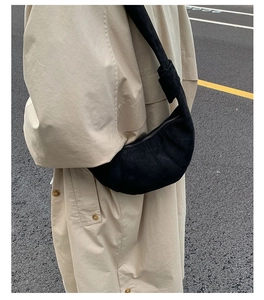 Détail du sac croissant noir matelassé avec bandoulière nouée sur un trench-coat beige chic