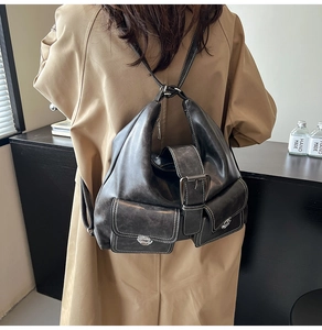 Detail of black vintage leather backpack with white stitching and three front buckled pockets