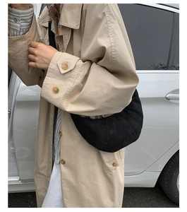 Détail du sac croissant en daim noir minimaliste avec coutures diagonales sur l'épaule