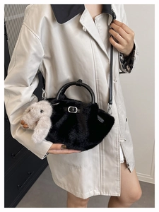 Detail of black faux fur bucket bag featuring plush rabbit pendant and leather handles