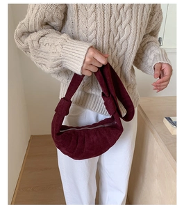 Détail du sac croissant bordeaux en daim avec texture plissée et bandoulière nouée