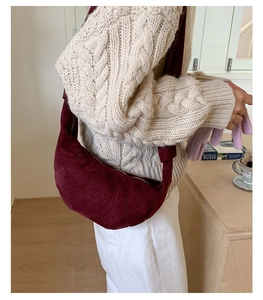 Gros plan du sac croissant bordeaux en daim avec détails de couture et fermeture éclair