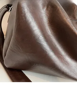 Close-up of vintage dark brown tote bag showing natural leather texture and soft wrinkles