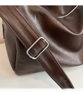 Detail of dark brown leather tote showing wide shoulder strap and silver metal buckle