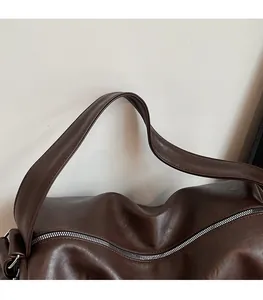 Detail of wide PU leather shoulder strap and smooth texture on dark brown tote bag