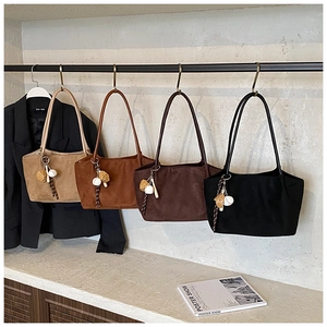 Detalle de bolsos tote de ante en cuatro colores con colgantes de béisbol en un expositor