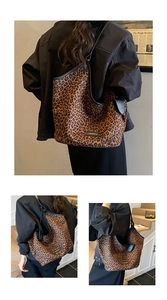 Macro shot of large leopard print tote bag with black leather straps and brand logo plate