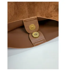 Close-up of golden magnetic buckle closure on a brown suede tote bag for women